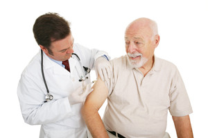 Senior man getting a flu shot from his doctor. Isolated